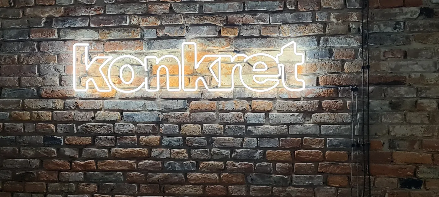 Biały neon „konkret” na ceglanej ścianie lokalu