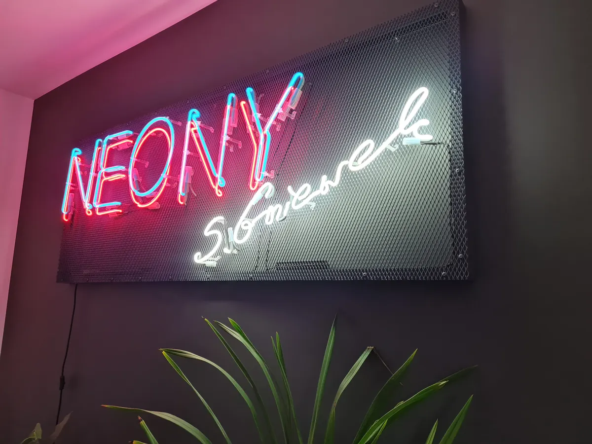Neon NEONY z podpisem na blasze perforowanej w lokalu